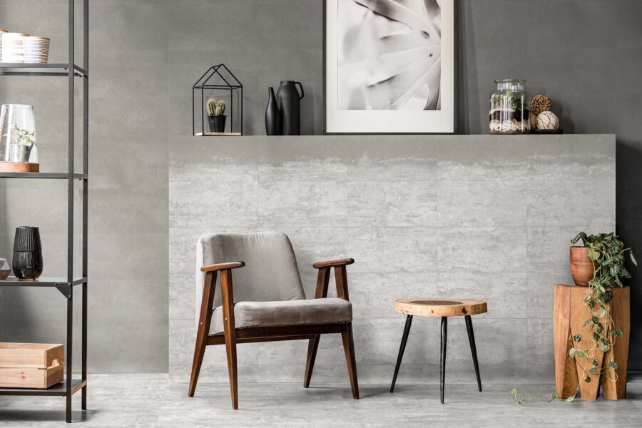Grey armchair next to a wooden table in living room interior with plant and poster